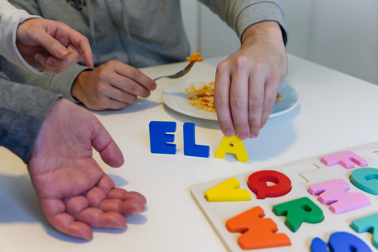 Manos colocando letras de ELA sobre una mesa con comida.