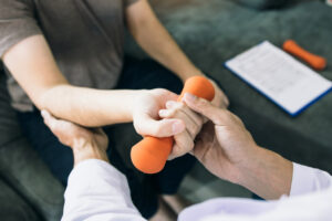 Persona sosteniendo un peso mientras recibe asistencia en un tratamiento de osteoporosis.