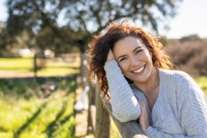 Mujer sonriente con cabello rizado en un entorno natural