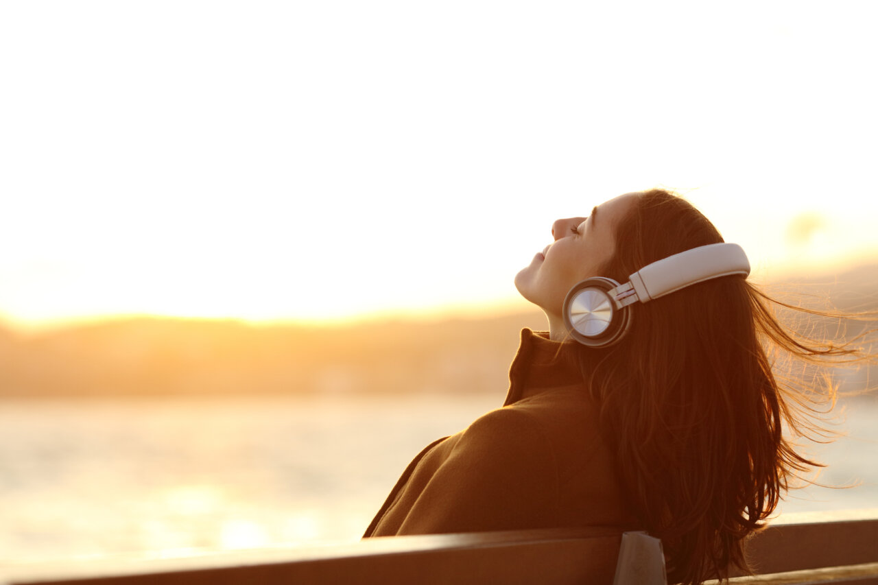 Mujer con auriculares disfrutando de la música al atardecer