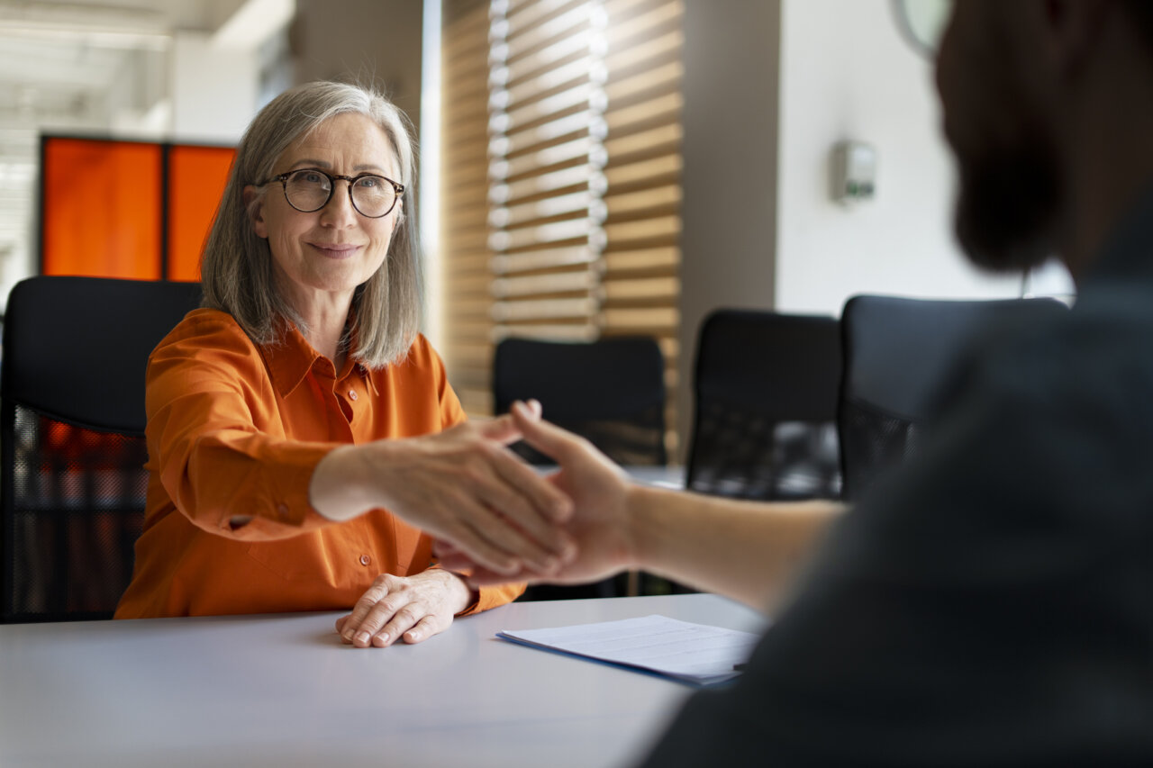 Profesional sénior en una entrevista de trabajo estrechando manos