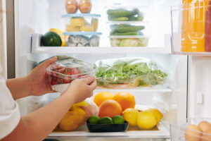 Persona organizando alimentos frescos en un refrigerador