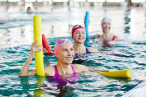 Mujeres mayores disfrutando de una clase de natación con flotadores